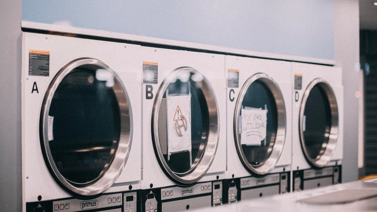 services-03 A series of industrial washing machines labeled A to D in a modern laundromat setting.